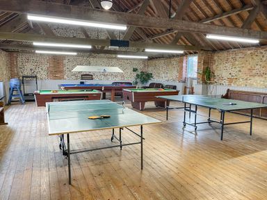 A game room with two ping pong tables a pool table and a snooker table with wooden floors at The Dairy Barn in Toftrees near Fakenham