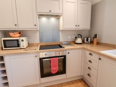 A kitchen with white cabinets oven stove microwave kettle toaster and knife set at Tawny Cottage in Irton Moor near Scarborough