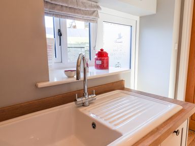A kitchen sink with a chrome faucet and red container on windowsill at Tawny Cottage in Irton Moor near Scarborough