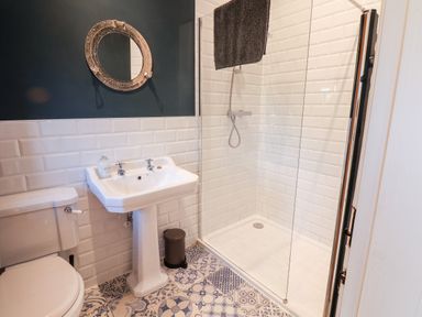 A bathroom with a toilet sink shower and round mirror at Tawny Cottage in Irton Moor near Scarborough