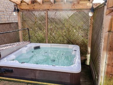 An outdoor hot tub with wooden lattice walls and a wooden pergola roof at Tawny Cottage in Irton Moor near Scarborough