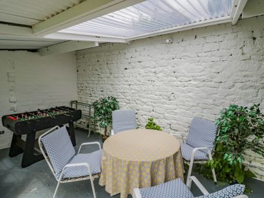 A room with a round table covered with a patterned tablecloth surrounded by four chairs and a foosball table at Priors Mead in Claydon near Cropredy