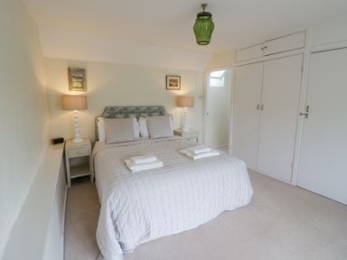A bedroom with a double bed, two bedside tables with lamps, built-in wardrobes, and a green ceiling light at Priors Mead Claydon near Cropredy