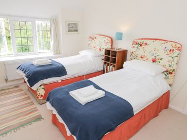 A bedroom with two single beds blue throws and floral headboards at Priors Mead in Claydon near Cropredy