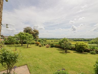 A garden with grass and trees overlooking fields at Priors Mead Claydon near Cropredy