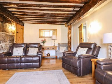 A living room with leather sofas wooden beams on the ceiling and a wooden floor at Cwm Yr Afon Mawr Llanbedr near Harlech