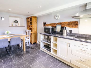 A kitchen with dining table and chairs next to cabinets and stove at Cwm Yr Afon Mawr Llanbedr near Harlech