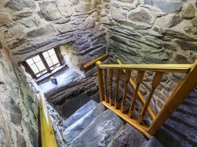 A stone staircase with wooden handrails and a window at Cwm Yr Afon Mawr in Llanbedr near Harlech