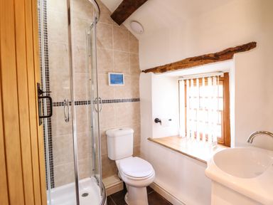A bathroom with a shower enclosure toilet sink and a window with blinds at Cwm Yr Afon Mawr in Llanbedr near Harlech