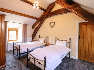 A bedroom with two single beds wooden beams on the ceiling a wooden door and a window at Cwm Yr Afon Mawr Llanbedr near Harlech