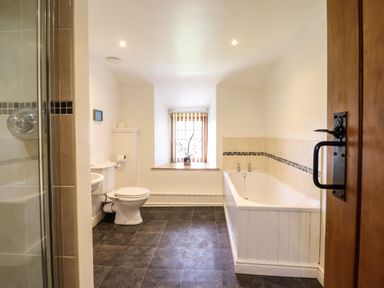 A bathroom with a bathtub toilet and window with blinds at Cwm Yr Afon Mawr in Llanbedr near Harlech