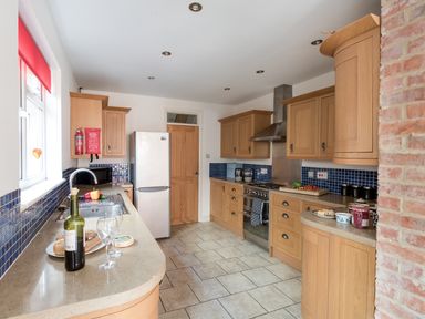 A kitchen with wooden cabinets a refrigerator and a countertop with wine bread and glasses at Sandsfoot Rest in Weymouth