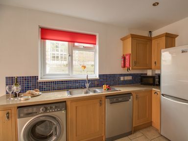 A kitchen with wooden cabinets a washing machine dishwasher microwave and refrigerator at Sandsfoot Rest in Weymouth