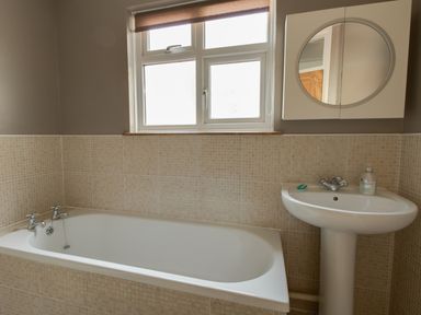 A bathroom with a bathtub sink a mirror and a window at Sandsfoot Rest in Weymouth