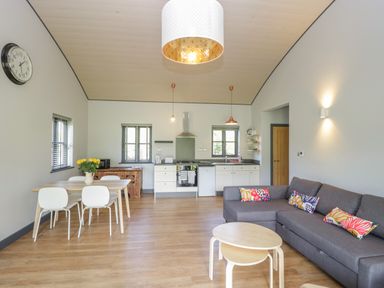 An open plan kitchen and living area with a dining table chairs gray sofa and round nesting tables at Foxglove Sticklinch West Pennard Glastonbury