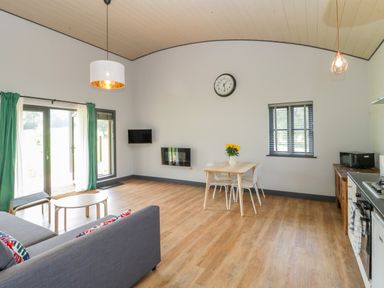 An open plan living room and kitchen with sofa table chairs and kitchen appliances at Foxglove in Sticklinch West Pennard Glastonbury