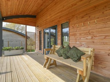 A wooden porch with a bench and cushions at Foxglove in Sticklinch West Pennard Glastonbury
