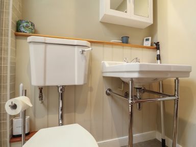 A bathroom with a white toilet and a white sink with metal legs at Courtyard Cottage Poplar Farm Barn Sweffling near Saxmundham