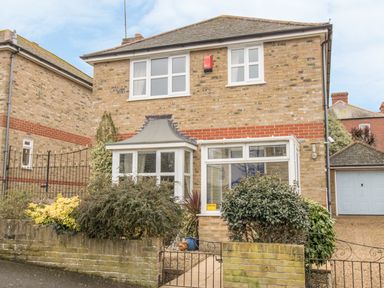 A two story brick house with white framed windows bushes and a small front garden at Casa Carmen Weymouth