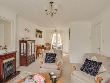 A living room with two armchairs a wooden coffee table a fireplace and a dining table at Casa Carmen Weymouth