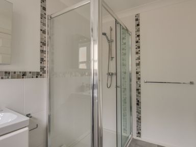 A bathroom with a glass shower enclosure a handheld shower head a towel bar and a sink with a mirror at Casa Carmen Weymouth
