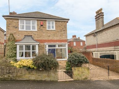 A two story brick house with white framed windows a small garden and metal gate at Casa Carmen Weymouth