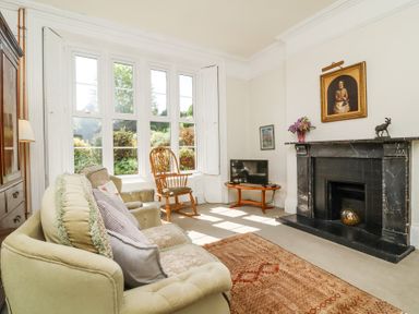 A living room with sofa armchair rocking chair fireplace and TV at The Old Vicarage in Tiverton