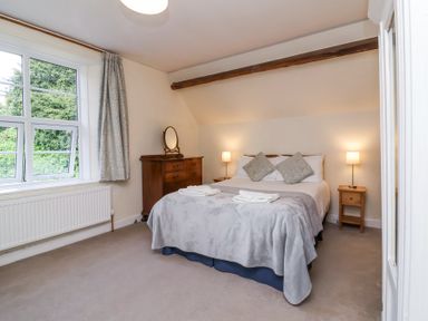 A bedroom with a bed bedside tables a wooden dresser and a window at The Old Vicarage in Tiverton