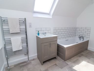 A bathroom with a bathtub a sink cabinet and a towel rack at The Old Vicarage in Tiverton