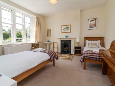 A bedroom with two single beds a fireplace and a piano at The Old Vicarage in Tiverton