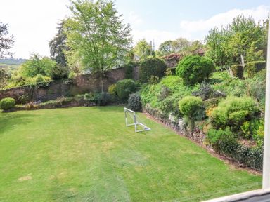 A garden with a small soccer goal on grass and various bushes and trees at The Old Vicarage in Tiverton
