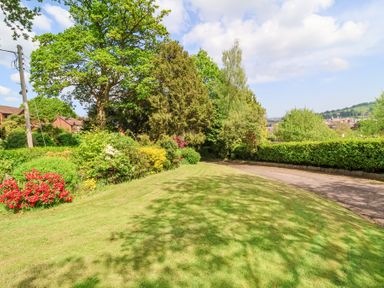 A grassy area with trees bushes and a path along the side at The Old Vicarage in Tiverton