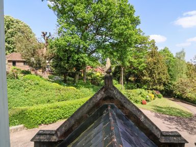 A garden with trees bushes and a lawn near a sloped roof at The Old Vicarage in Tiverton