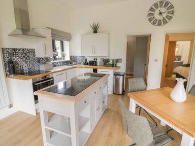 A kitchen with an island, dining table with chairs, and patterned backsplash at The Barn in Droitwich Spa