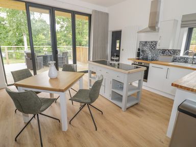 A kitchen with a dining table chairs kitchen island oven and sliding glass doors leading to an outdoor dining area at The Barn in Droitwich Spa
