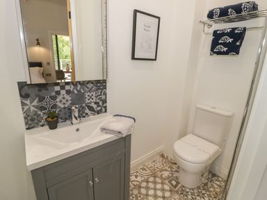 A bathroom with a toilet a sink under a mirror and towels on a rack at The Barn in Droitwich Spa