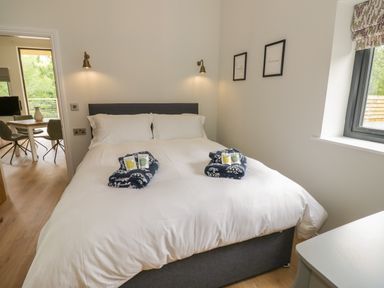 A bedroom with a double bed with white bedding and folded towels on the bed at The Barn in Droitwich Spa