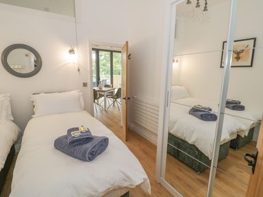 A bedroom with a single bed with towels on it a round mirror on the wall and a wardrobe with mirrored doors at The Barn in Droitwich Spa