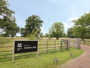 A country road entrance with a National Trust sign for Hanbury Hall and trees in the background