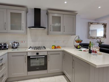 A modern kitchen with gray cabinets a gas stove a stainless steel oven toasters and a fruit basket on the counter at Low Tide in Weymouth