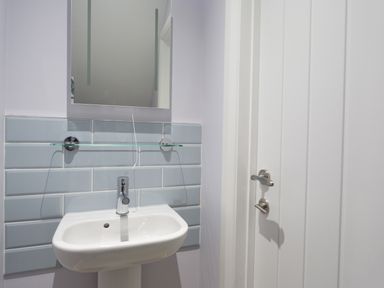 A bathroom sink with a faucet a mirror a glass shelf and a white door at Low Tide in Weymouth