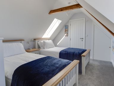 A bedroom with two single beds with blue blankets under a skylight at Low Tide in Weymouth