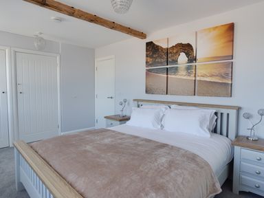 A bedroom with a wooden bed white bedding two bedside tables and a six-piece wall art above the bed at Low Tide in Weymouth