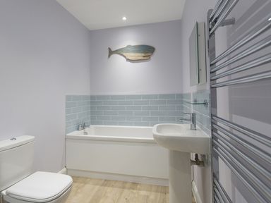 A bathroom with a toilet sink bathtub and towel warmer at Low Tide in Weymouth