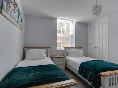 A bedroom with two single beds a window between them a nightstand and a closet at Low Tide in Weymouth