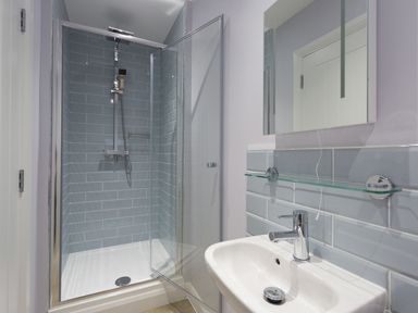 A bathroom with a glass shower enclosure white sink and mirror at Low Tide in Weymouth