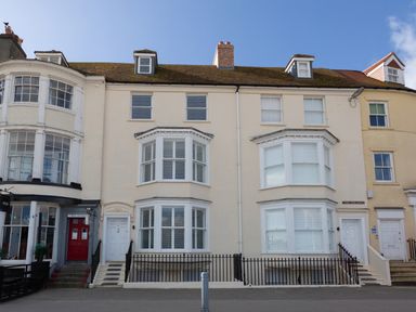 A row of cream-colored townhouses with bay windows and white doors at Low Tide in Weymouth