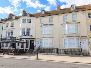 A street view of terraced buildings with a restaurant and residential entrances at Low Tide in Weymouth