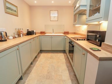 A kitchen with cabinets toaster kettle microwave and sink at The Garden Cottage in West Woodburn