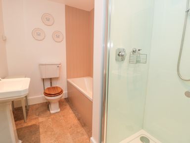 A bathroom with a toilet a bathtub a shower and a sink at The Garden Cottage in West Woodburn